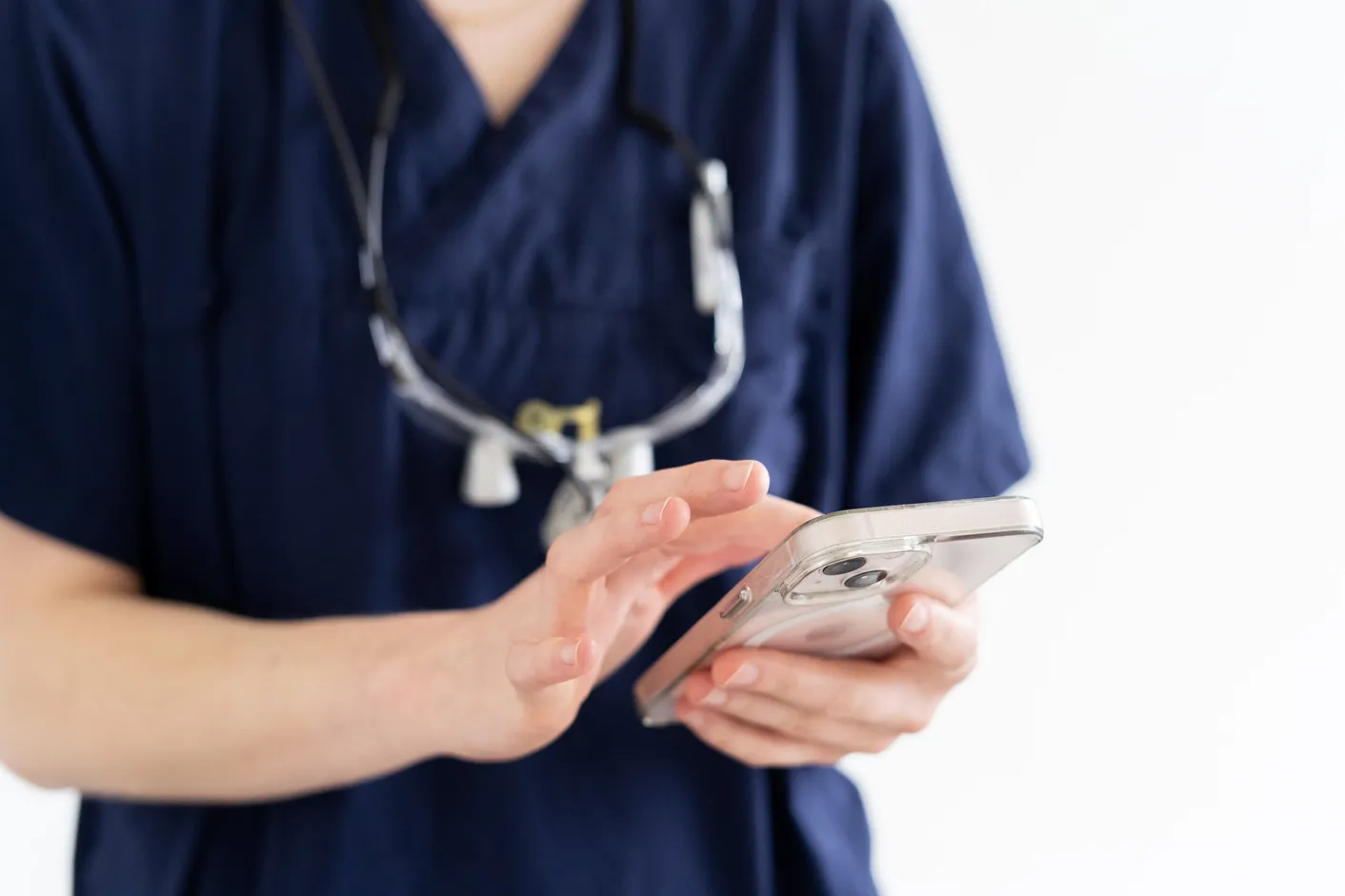 Behandler im dunkelblauen Kasack dokumentiert eine Behandlung digital auf dem Smartphone